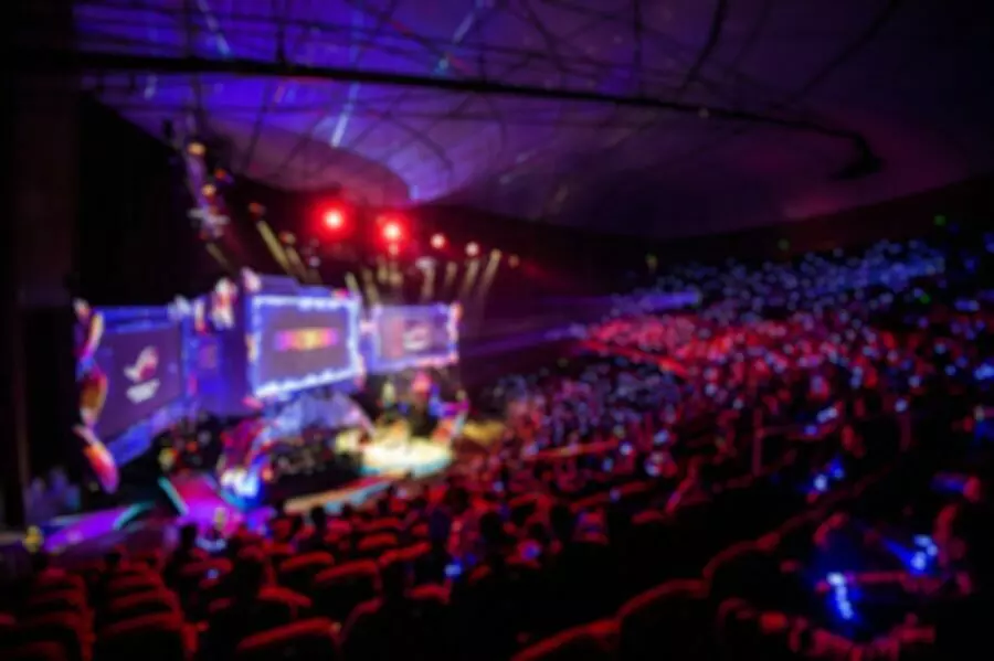 Blurred background of esports event at big arena with a lot of lights and screens
