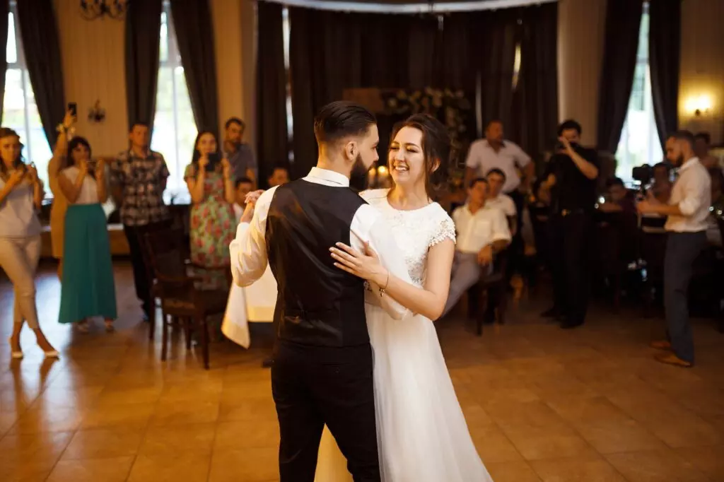 Happy bride, groom is cutting their stylish wedding cake on wedding banquet. Elegant wedding cake.